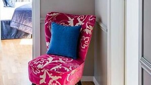 Een hoekkamer met een stoel met een rood-wit patroon, een witte airconditioning en een deur naar een andere kamer.