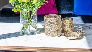 Een woonkamer met een bank, een vaas met groene planten en decoratieve items op een tafel.