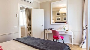 Une chambre d’hôtel avec un lit, un bureau, une chaise et un miroir.