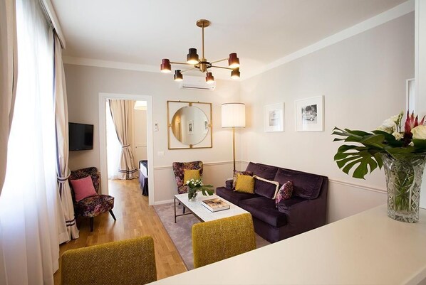 A modern living room with a sofa, armchairs, a coffee table, and a TV.