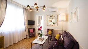 Un salon comprenant un canapé, des fauteuils, une table basse, un téléviseur et une lampe.