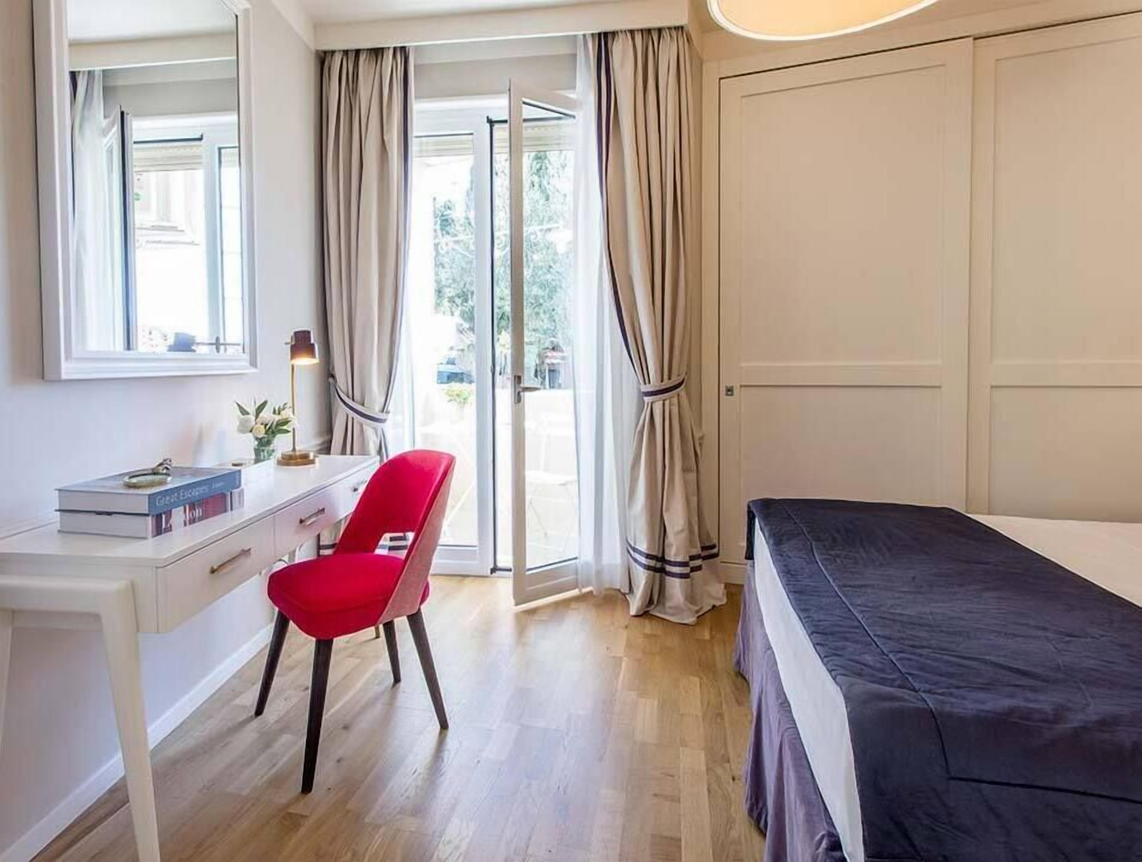 A bedroom with a bed, a desk, a chair, and a window.
