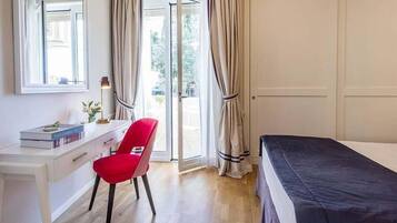 A bedroom with a bed, a desk, a chair, and a window.