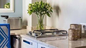 A modern kitchen with white cabinets, a gas stove, a toaster, and decorative items on the shelves.