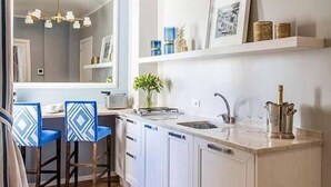A modern kitchen with white cabinetry, a central island with a sink, and a dining area with blue chairs.