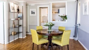A dining area with a round table, yellow chairs, and a vase with flowers.