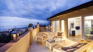 A balcony with a glass door leading to a room, furnished with a sofa, chairs, and a table. - Blue Penthouse (Taormina)