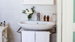 A bathroom with a white sink, a mirror, and two wall-mounted lamps.