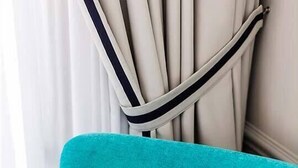 A teal armchair with a yellow and white patterned pillow.
