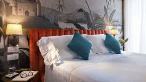 A hotel room with a bed, two pillows, a nightstand with a lamp, a glass of water, and a book. - Green Palm (Taormina)