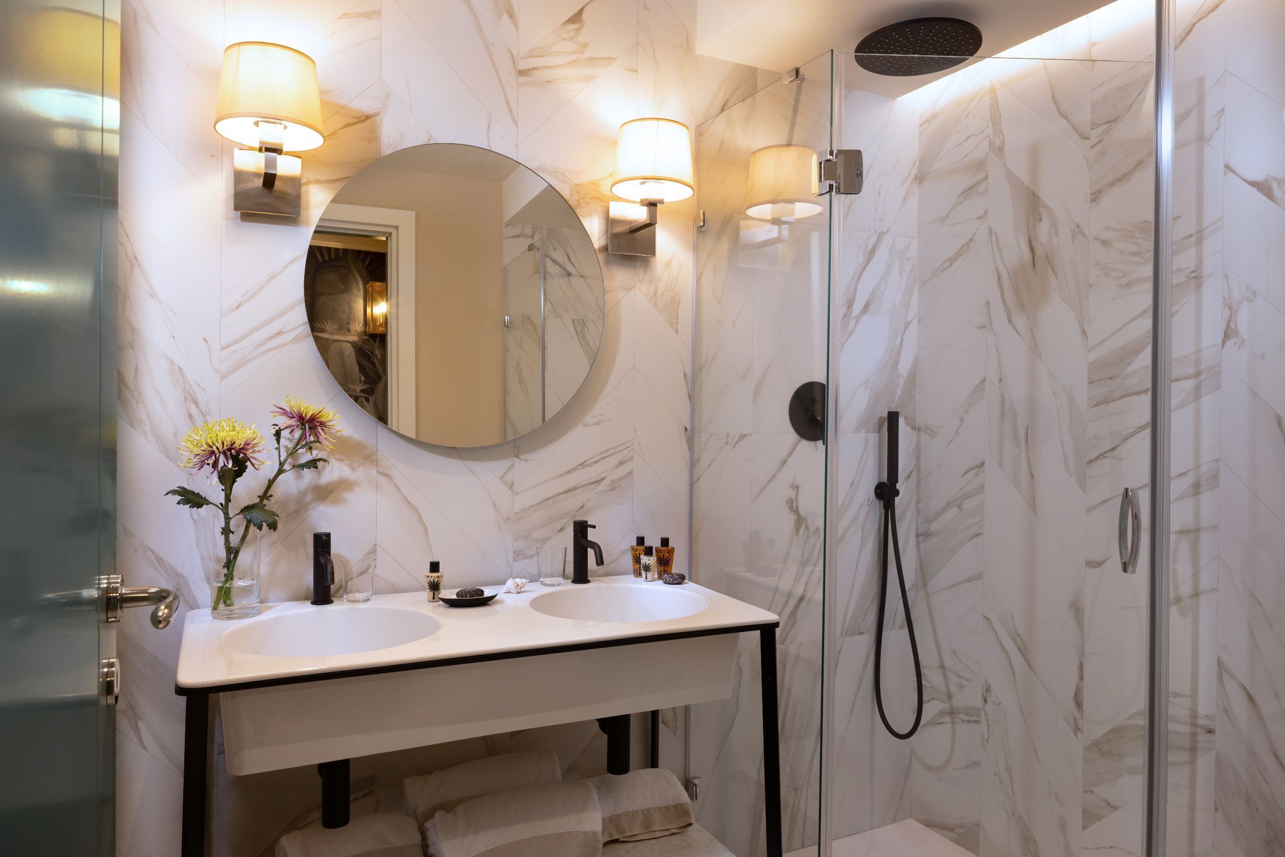 A bathroom with a double sink, a mirror, and a shower.