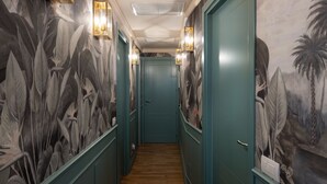 A hallway with a wooden floor, teal walls, and a door at the end. - Green Palm (Taormina)