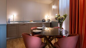 A modern kitchen with a dining area, featuring a glass table, red chairs, and a vase with flowers. - Green Palm (Taormina)