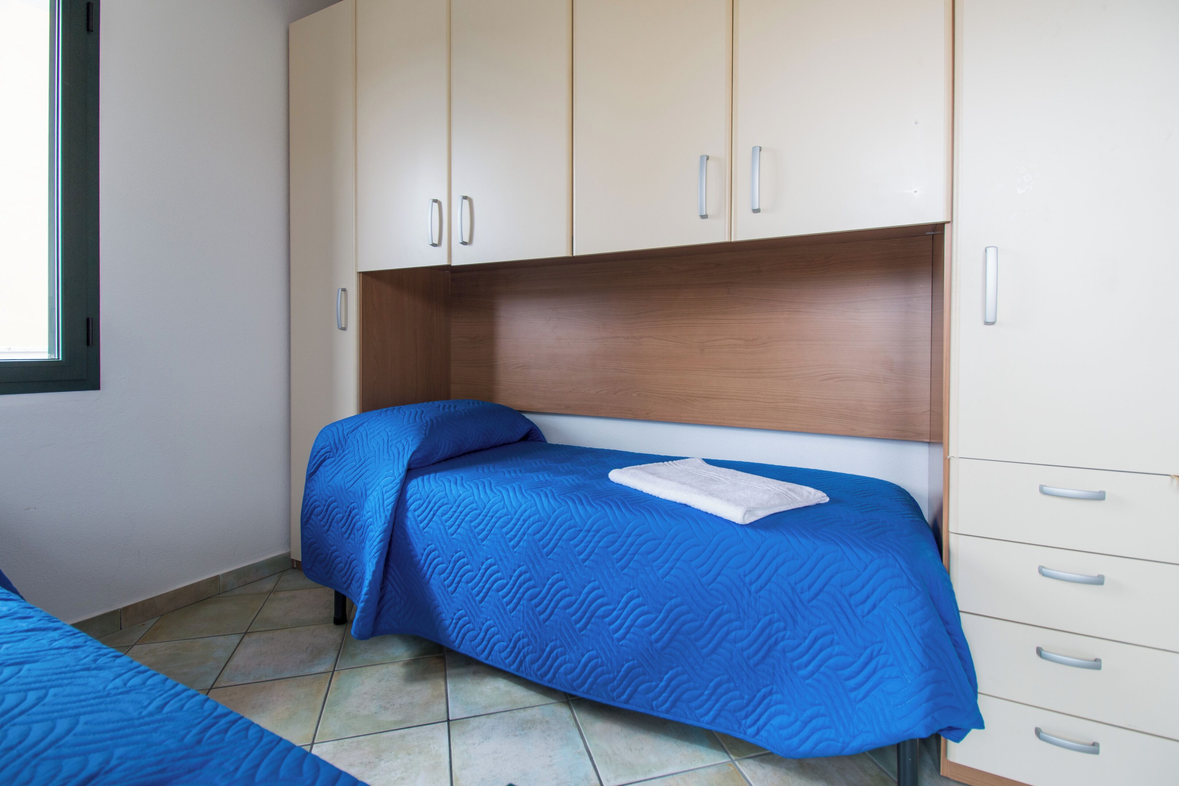 Un dormitorio con cama, armario y ventana.