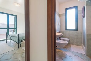 A bedroom with a bed, a bathroom with a toilet and sink, and a large window. - Residence Maria Antonia - Grazia Deledda (Orosei)
