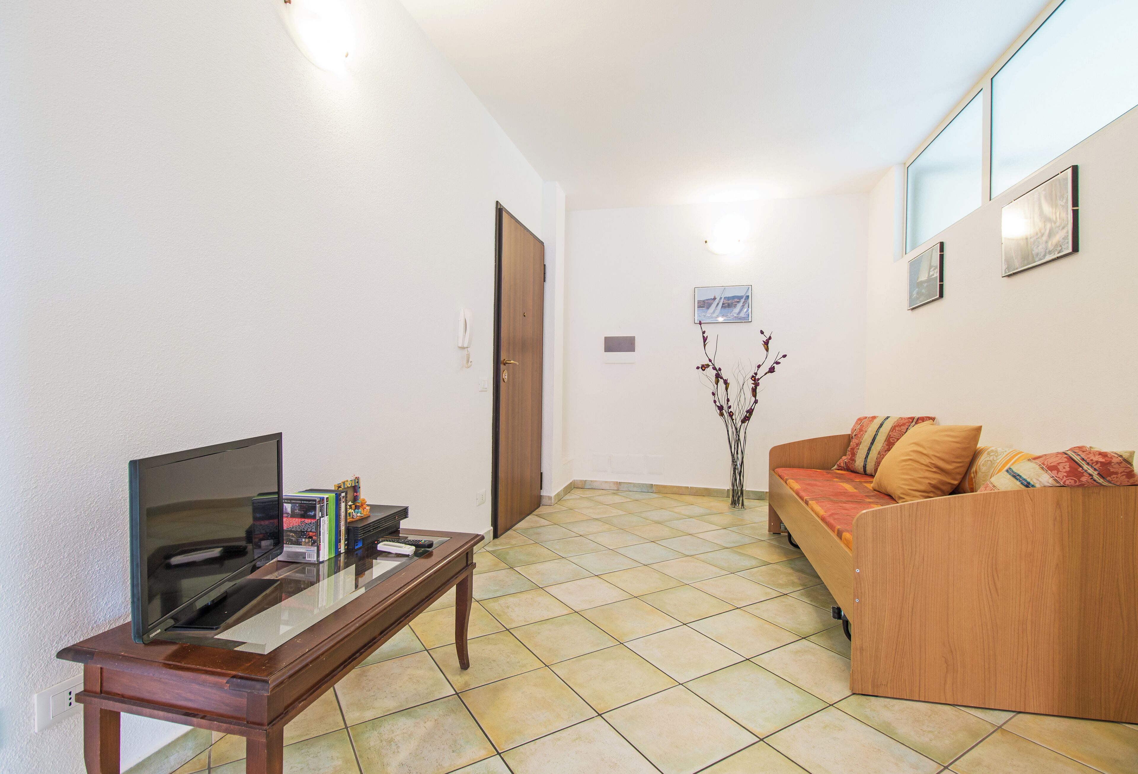 A living room with a flat-screen TV, a wooden coffee table, a sofa, and a small decorative plant.