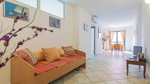Una sala de estar con un sofá, un televisor y un comedor con mesa y sillas.