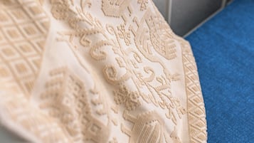 A close-up of a textured fabric with intricate patterns, likely part of a bedspread or upholstery.