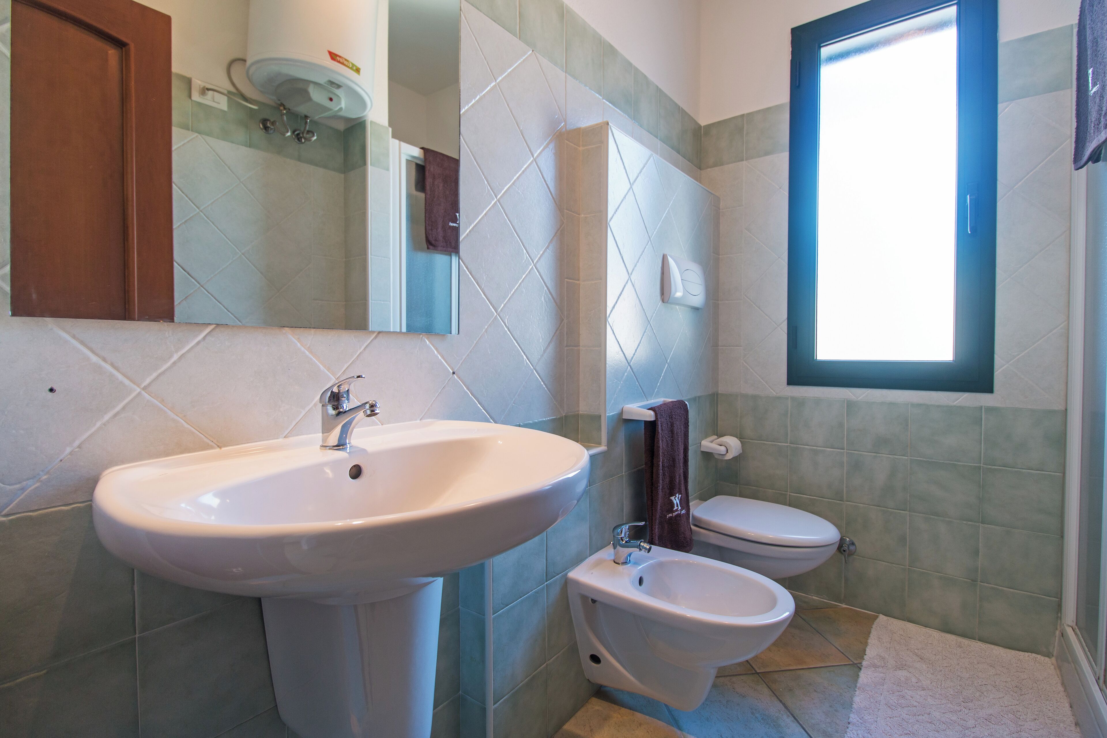 Une salle de bain équipée d’un lavabo, d’un bidet, de toilettes et d’une fenêtre.