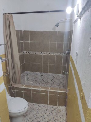 Een douche, handdoeken, zeep, toiletpapier