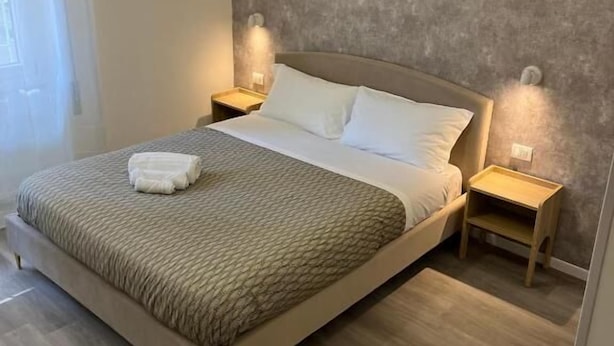 Une chambre moderne avec un grand lit, des tables de chevet en bois et des luminaires suspendus.