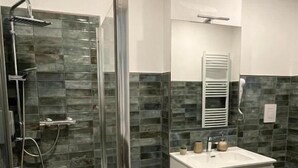 Une salle de bain moderne avec une douche à parois de verre, un meuble-lavabo blanc avec un miroir et des toilettes.