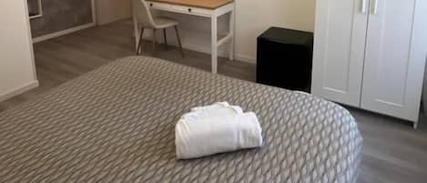 A modern bedroom with a bed, a desk, a TV, and a wardrobe.