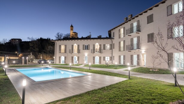 Un edificio moderno con piscina, iluminación exterior y una torre al fondo.