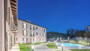 Un edificio moderno con piscina, senderos pavimentados e iluminación exterior.
