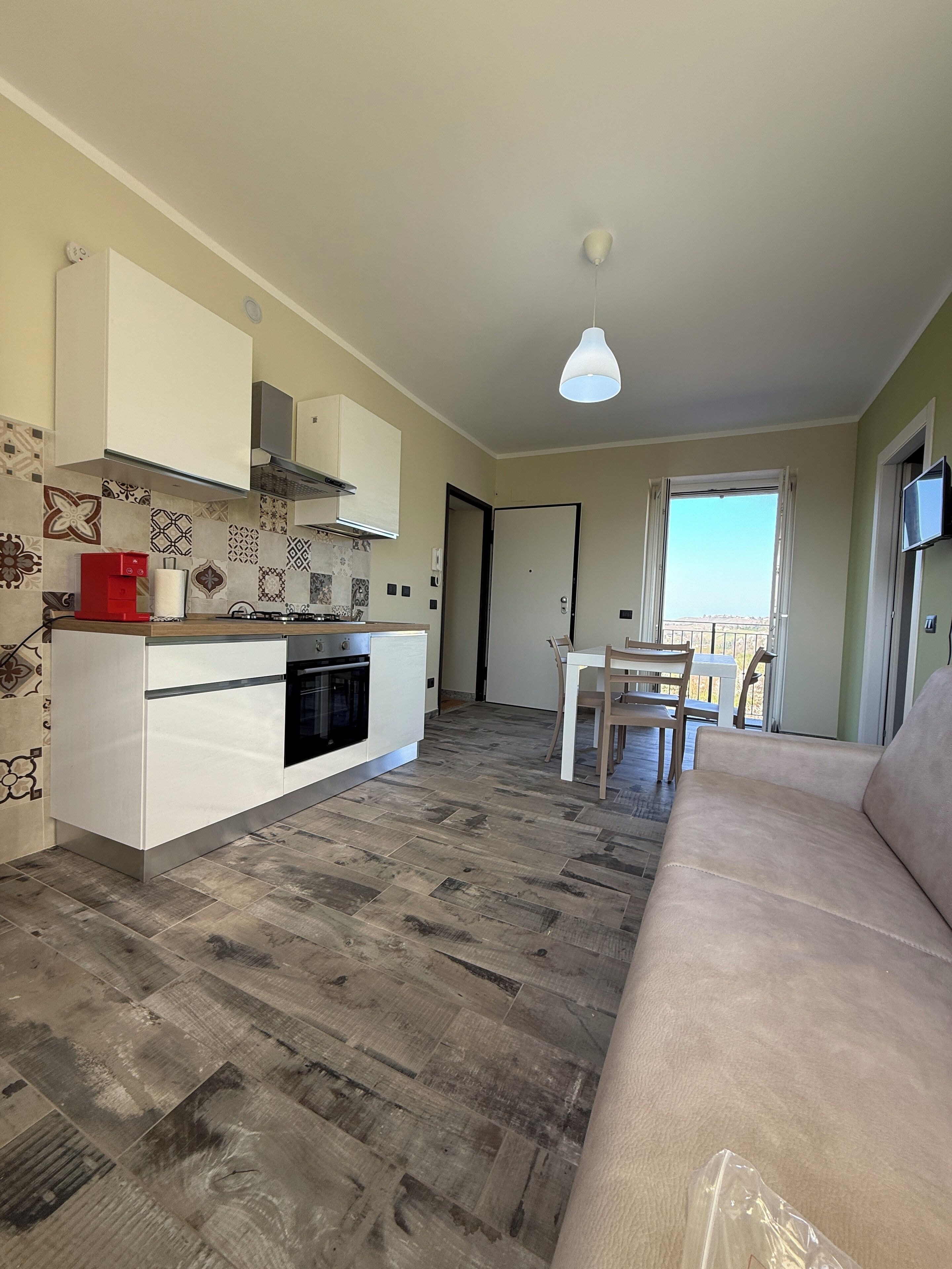Un espacio habitable compacto con kitchenette, comedor y sofá.