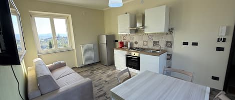A compact kitchen with a dining area, a sofa, and a TV.