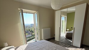 Un dormitorio con una cama grande, un radiador, una ventana con vistas y una lámpara en el techo.