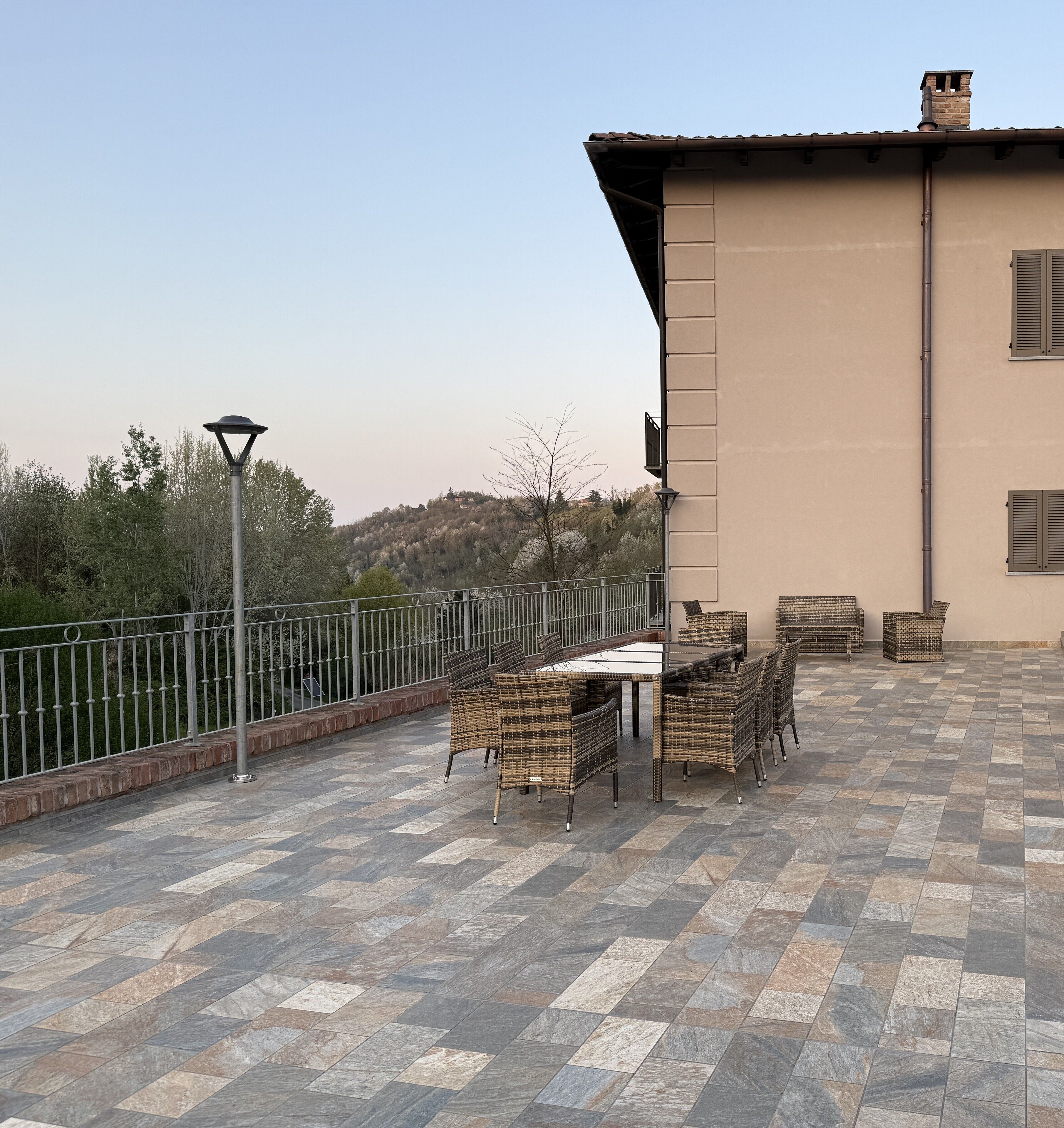 An outdoor patio with a table and chairs, a lamp, and a view of a hill.