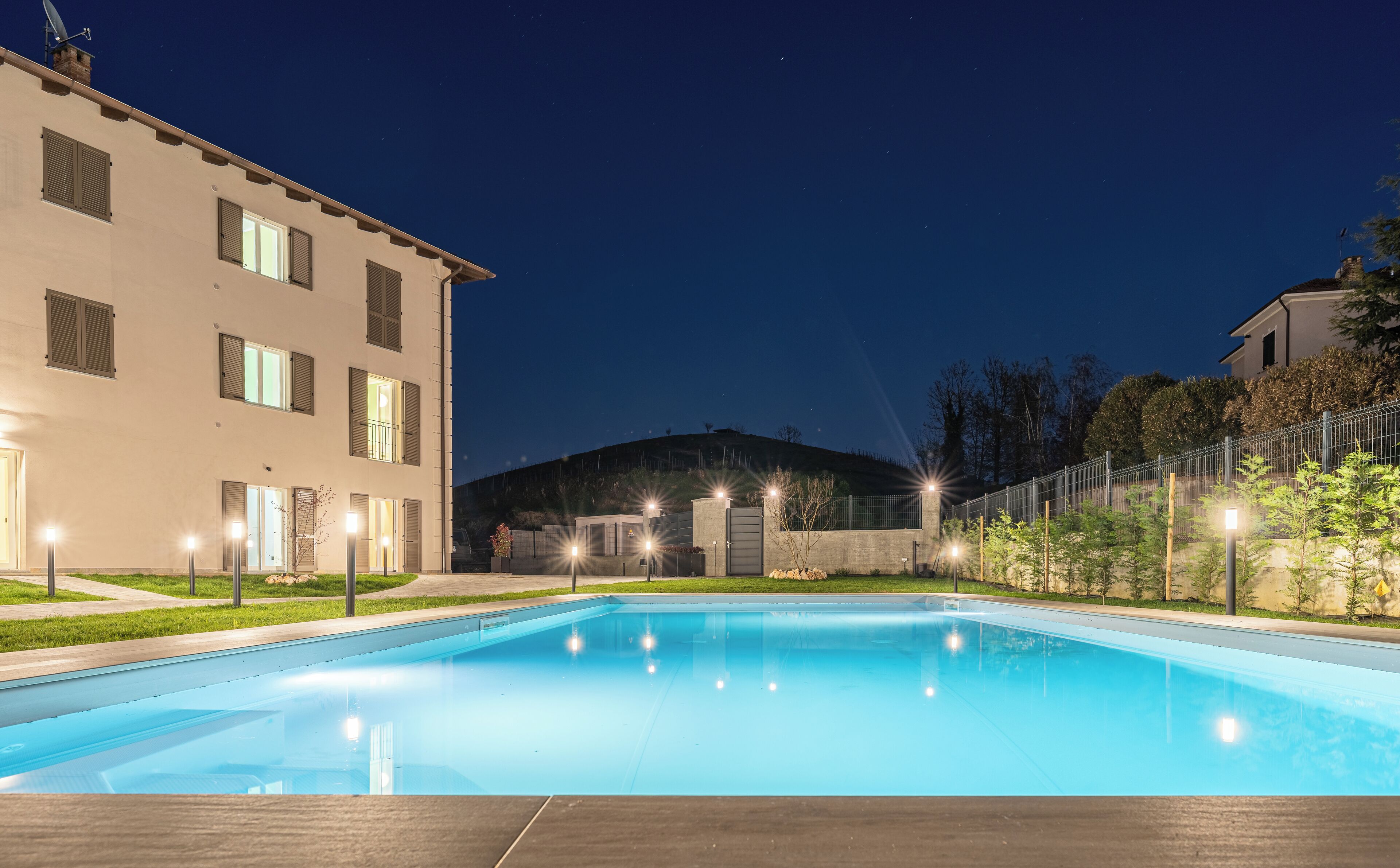 Ein Schwimmbecken mit Blick auf ein Gebäude mit vielen Fenstern und eine Hügelkulisse im Hintergrund.