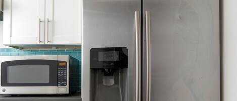Un refrigerador de acero inoxidable con microondas integrado, dispensador de agua y compartimento congelador.