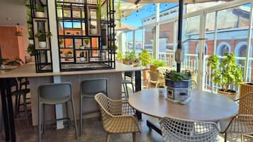 A cafe with a bar area, outdoor seating, and potted plants.