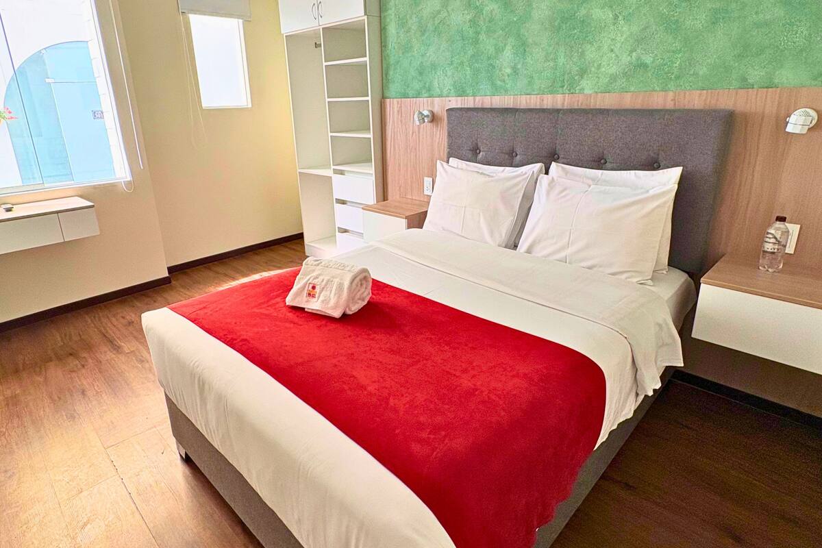 Ein Hotelzimmer mit Bett, Nachttisch, Kleiderschrank und Fenster.