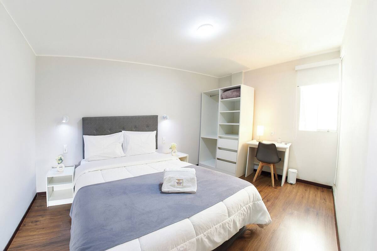 Ein Schlafzimmer mit Bett, Nachttischen, Schreibtisch und Kleiderschrank.