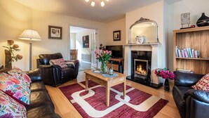 A living room with a fireplace, leather sofas, a coffee table, and a bookshelf.