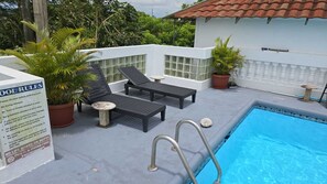 A rooftop pool area with lounge chairs, a small table, and a sign with pool rules. - Dalkeith Greathouse-Ultimate Vacation Rental (Knockpatrick)
