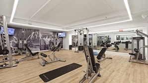 Une salle de sport moderne équipée de divers appareils d’exercice, d’un tapis noir et d’un grand miroir.