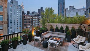 Une terrasse sur le toit avec des sièges extérieurs, un foyer et des plantes en pot.