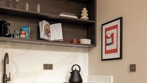 Une cuisine dotée d’un plan de travail en marbre, de meubles en bois et d’une bouilloire.