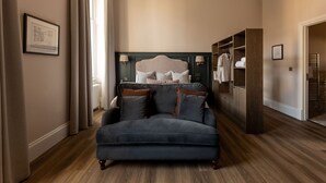 Une chambre à coucher avec un grand lit, un canapé bleu foncé et un dressing.