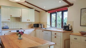 Una cocina con armarios de madera, un microondas, un tostador y una ventana con vistas a árboles.