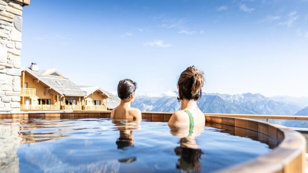 Dos personas en un jacuzzi con vistas a la montaña.
