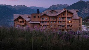 Un edificio de madera de varios pisos con balcones, con montañas al fondo.