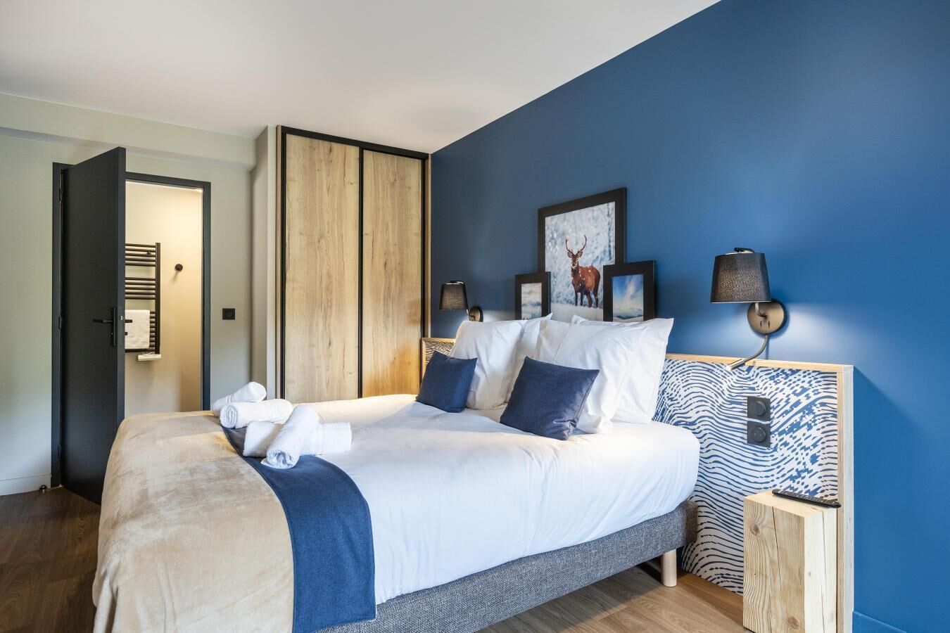 Ein modernes Schlafzimmer mit einem großen Bett, einem Holzschrank und einer blauen Akzentwand.