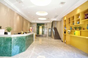 Un hall d’hôtel comprenant un comptoir d’accueil, un escalier et un mur avec des étagères.