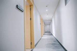 A long, narrow hallway with wooden doors on the left and a carpeted floor. - Xinrenren Hotel (Shanghai Daning International Zhabei Park Branch) (Shanghai)